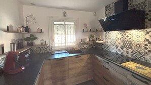 A modern kitchen with a central island, wooden cabinets, and patterned backsplash.