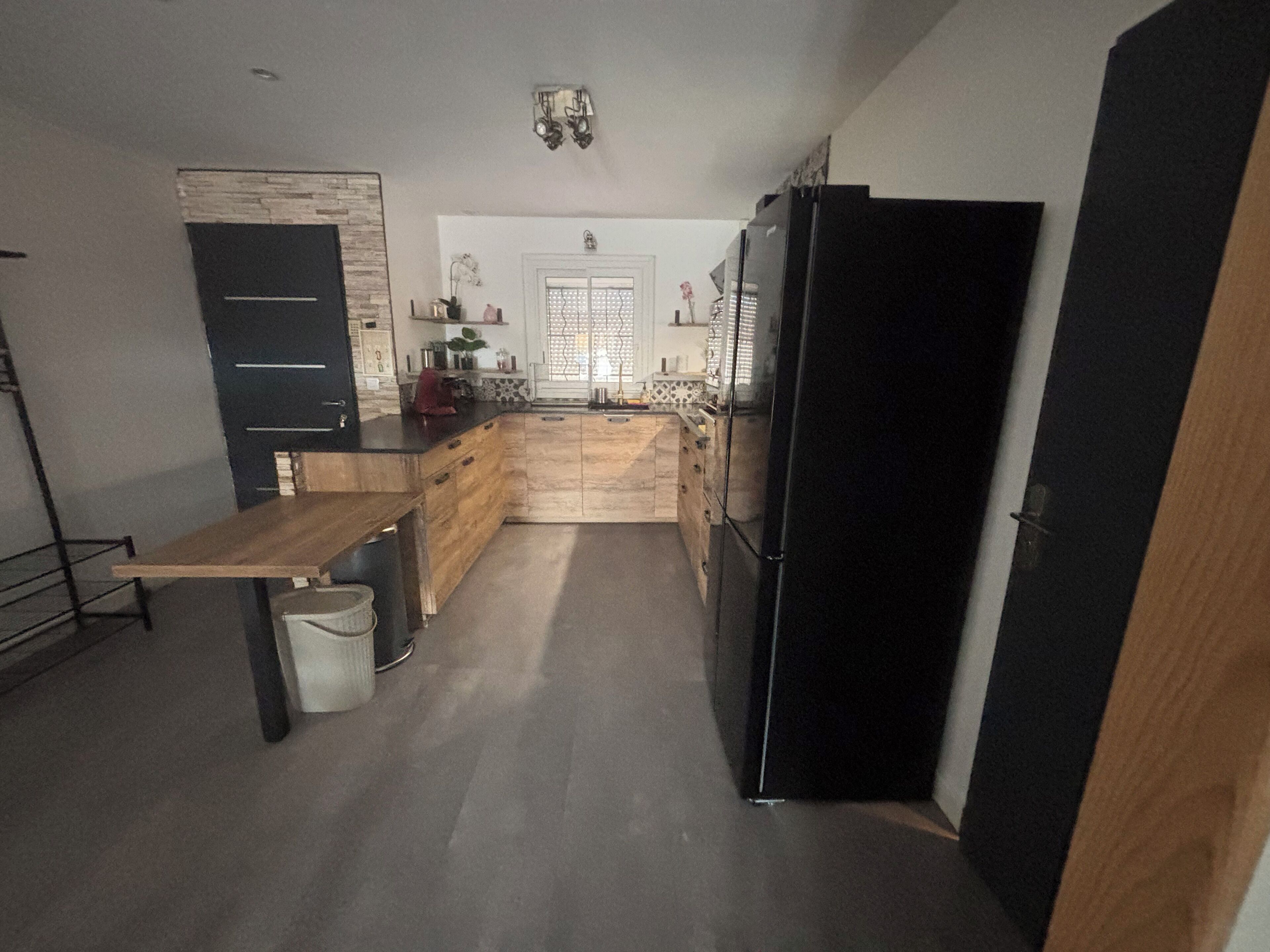 A modern kitchen with a wooden countertop, a black refrigerator, and a sink.
