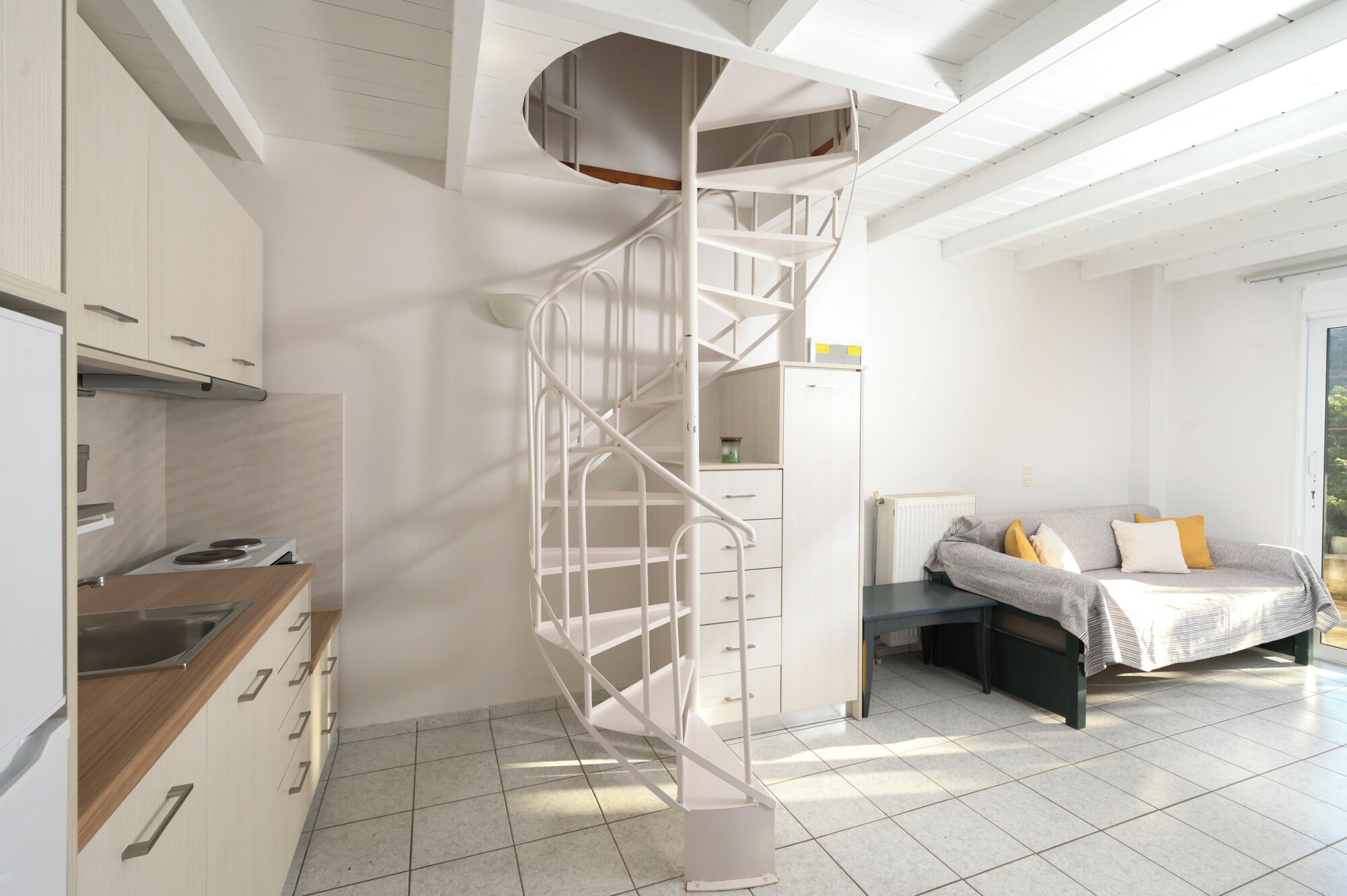 Ein modernes Interieur mit Küche, einer Wendeltreppe und einem Bett mit Aussicht.