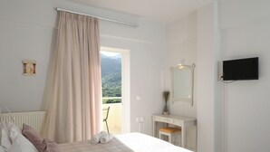Un dormitorio con una cama, un escritorio, un espejo y un televisor.
