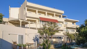 Un edificio de varios pisos con balcones, mobiliario exterior y plantas en macetas.