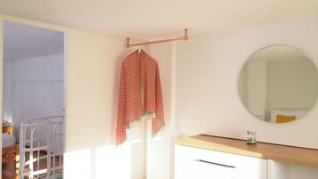 A bedroom with a bed, a wardrobe, a mirror, and a window.