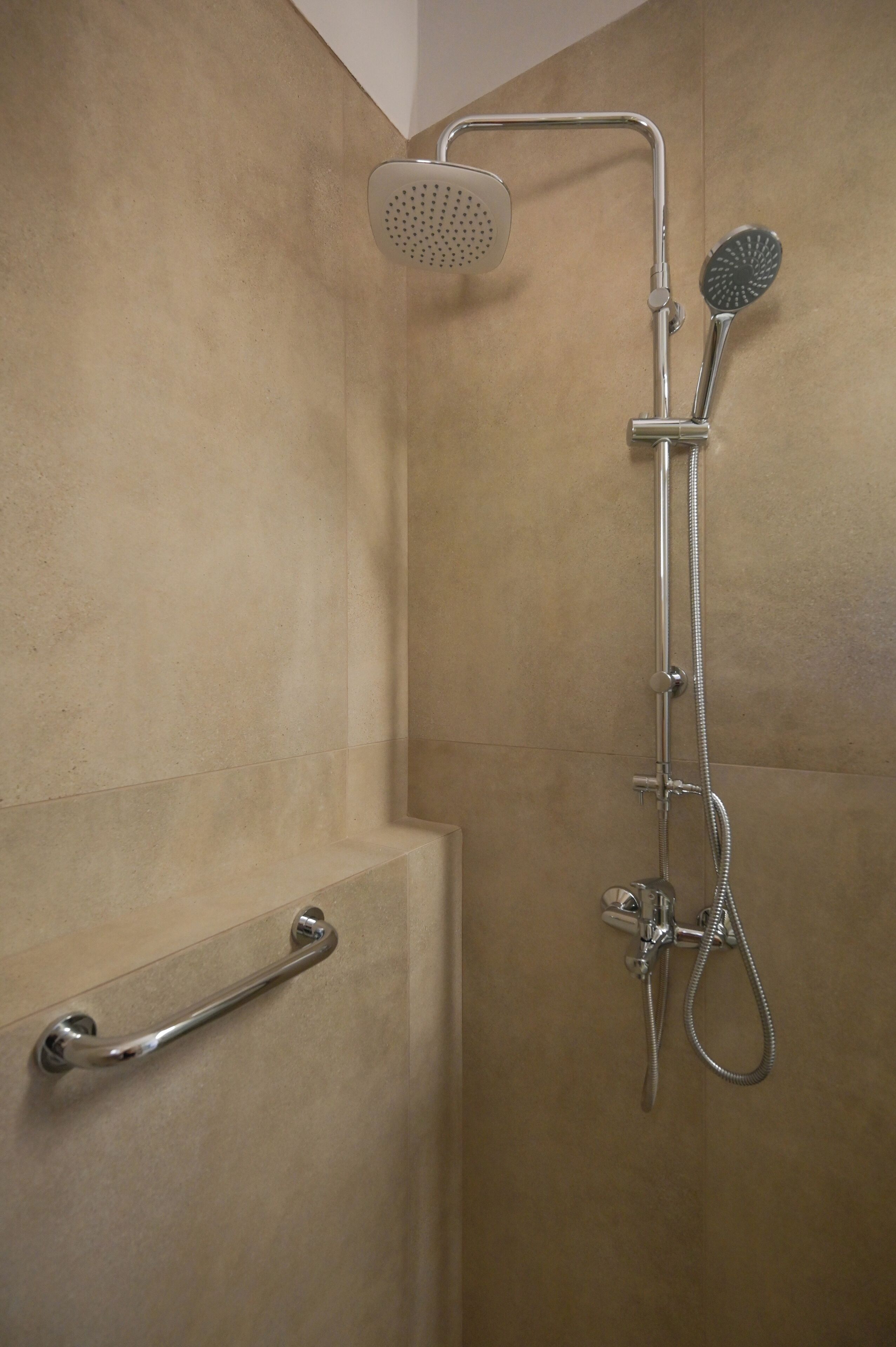 Een douche met een handdouche, een handscrubborstel en een douchebus.