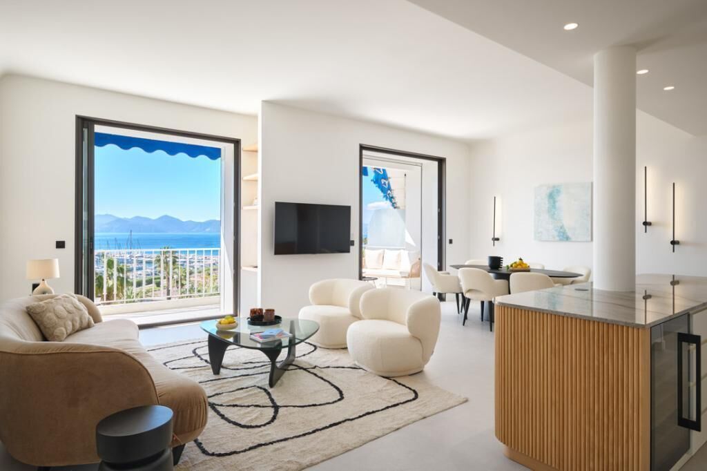 A modern living room with a sofa, coffee table, and a view of the sea.