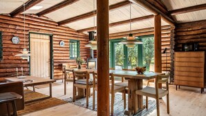 A rustic log cabin interior with a dining area, wooden furniture, and a large window offering a view of the outdoors. - Beautiful home in Præstø with WiFi (Præstø)