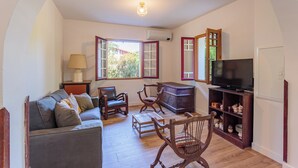A cozy living room with a sofa, chairs, a TV, and a wooden cabinet. - Appartement Gracieuse - Welkeys (Soorts-Hossegor)