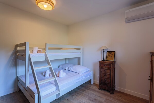 Una cama litera con escalera, un aparador de madera y un cuadro en la pared.