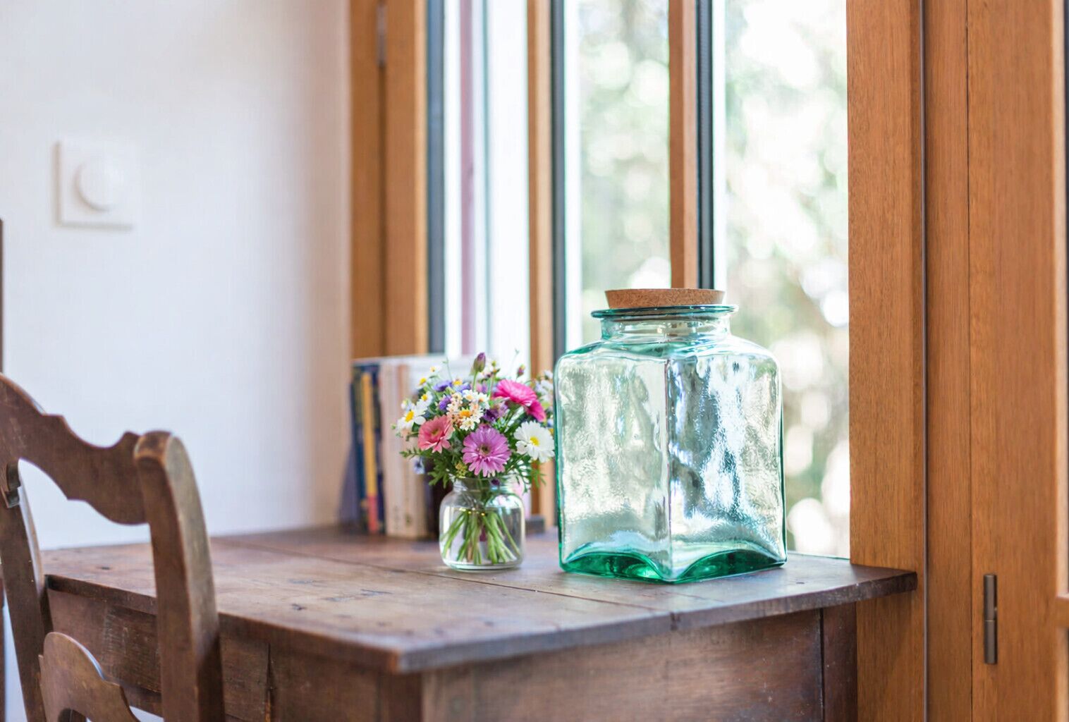 Ein Holztisch mit einem Glasbehälter und einer kleinen Blumenvase.