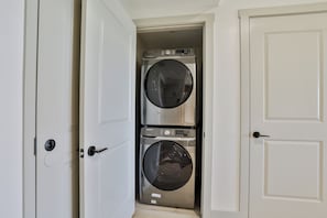 A compact laundry room with two stacked front-loading washing machines.