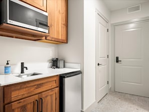 A kitchen with wooden cabinets, a dishwasher, a coffee maker, and a hand soap dispenser.