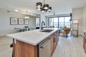 A modern kitchen with a large island, a dining area, and a view of the ocean.