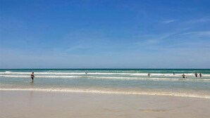 A beach with clear skies and calm waters. - Walk to Beach, Pool & Flagler! Relaxed Condo w/ Balcony & Full Kitchen (New Smyrna Beach)