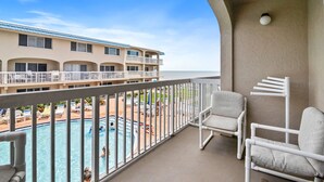 A balcony with a view of a swimming pool and a building with multiple balconies. - Walk to Beach, Pool & Flagler! Relaxed Condo w/ Balcony & Full Kitchen (New Smyrna Beach)