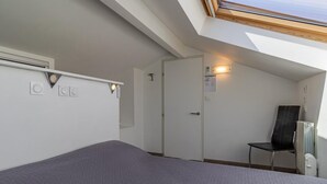 A bedroom with a skylight, a bed, a chair, and a radiator. - Maison Marmillons - Pavilion (AIX LES BAINS)
