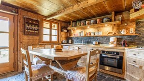 A rustic wooden kitchen with a stone floor, wooden cabinets, and a variety of kitchen appliances.