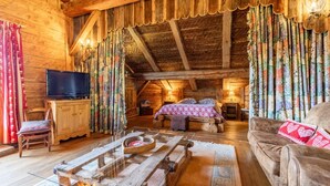 A rustic wooden room with a bed, a television, and a wooden table.