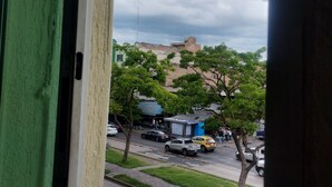 A view from a window overlooking a street with parked cars and a building in the background. - Hotel Astur (Guadalajara)