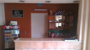 A reception area with a tiled counter, a refrigerator stocked with beverages, and a door in the background. - Hotel Astur (Guadalajara)