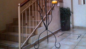 A staircase with a metal railing and a decorative black metal stand with orange spheres. - Hotel Astur (Guadalajara)