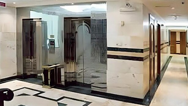 A modern hotel lobby with a marble floor, a reception desk, and a glass elevator. - Dar Alslama Apartment (Jeddah)