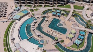 An aerial view of a resort with multiple swimming pools, sun loungers, and a central circular pool. - Las Palomas Phase 2 Coronado 1407 2 BR 2 BA (Puerto Peñasco)