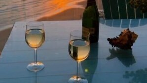 A table with two glasses of white wine and a bottle, set against a sunset view. - Las Palomas Phase 2 Coronado 1407 2 BR 2 BA (Puerto Peñasco)