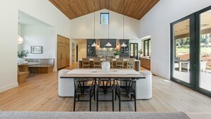 A spacious kitchen with a large island, wooden ceiling, and pendant lighting.