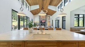 A spacious kitchen with a large island, wooden cabinets, and pendant lighting.