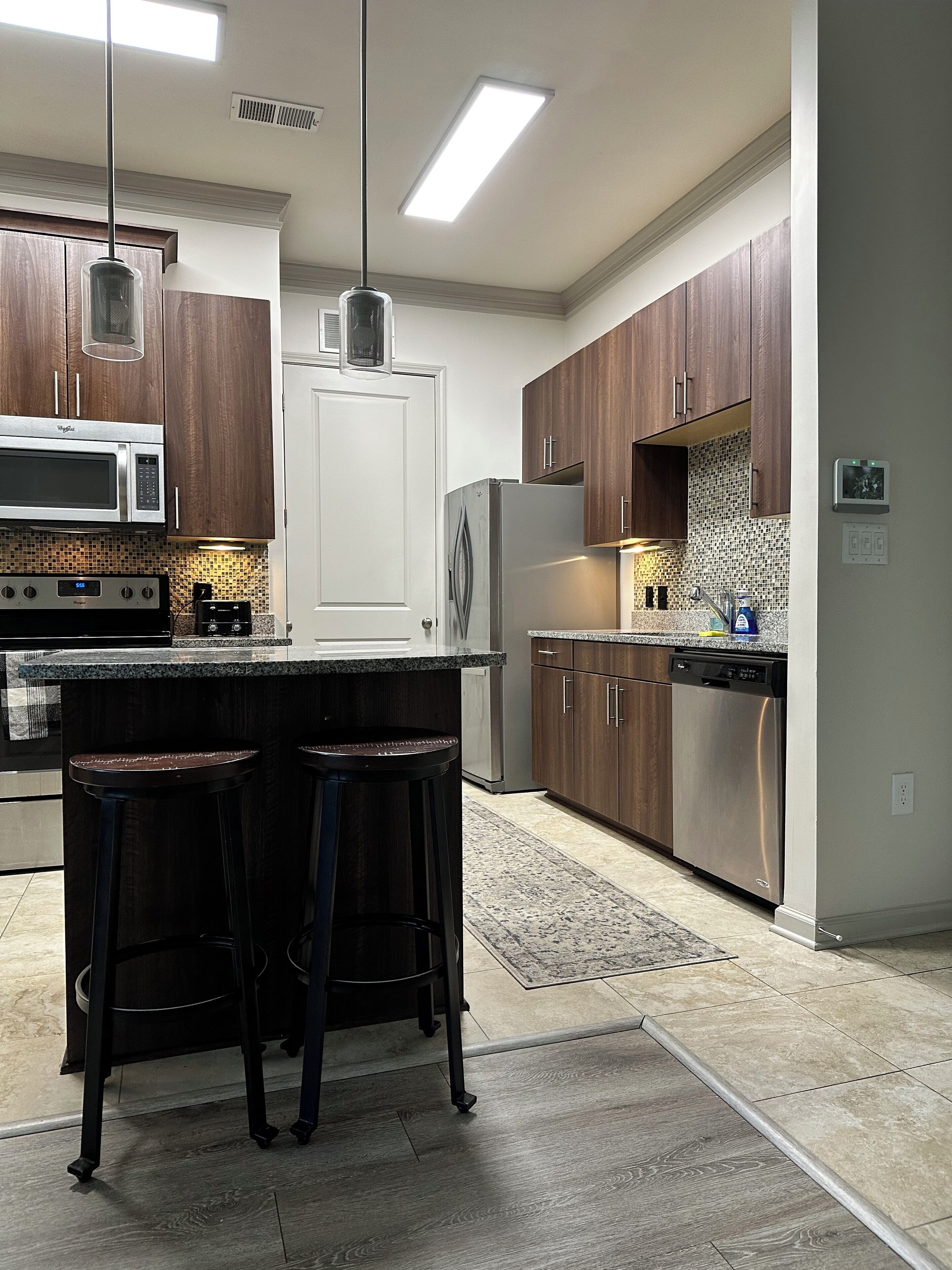 A modern kitchen with dark wood cabinets, stainless steel appliances, and a central island with bar stools.