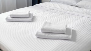 A neatly made bed with white linens and two folded towels on the side. - Stawy Brustmana Homly Apartment (Warszawa)