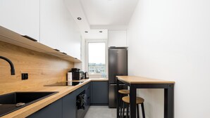 A modern kitchen with a wooden countertop, stainless steel appliances, and a view of the city through a window. - Stawy Brustmana Homly Apartment (Warszawa)