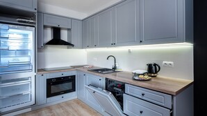 Een moderne keuken met grijze kastjes, een inbouwoven, een vaatwasser en een roestvrijstalen waterkoker.