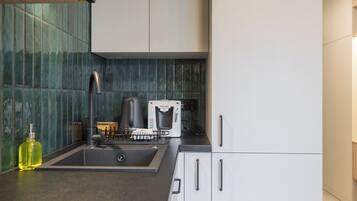 Een moderne keuken met een ingebouwde espressomachine, een spoelbak en een aanrecht met een fles olijfolie.