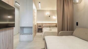 Et moderne hotelværelse med et fladskærms-TV, et klædeskab, en seng, et natbord og en lampe.