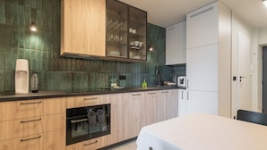 Eine moderne Küche mit Holzschränken, einem Einbauofen und einem Essbereich mit einem Tisch.