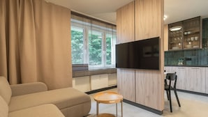 Ein modernes Wohnzimmer mit einer Couch, einem kleinen Holztisch und einem an einer Holzwand montierten Fernseher.