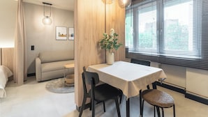 Ein moderner Essbereich mit Tisch, Stühlen, einer Blumenvase und einer Couch.