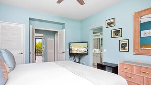 A bedroom with a bed, a television, a dresser, and a mirror.