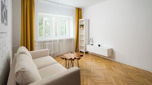 A modern living room with a sofa, a wooden coffee table, a white shelving unit, and a radiator. - Nowolipki Bright Studio (Warszawa)