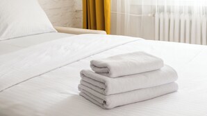 A neatly made bed with white linens and a stack of folded towels. - Nowolipki Bright Studio (Warszawa)