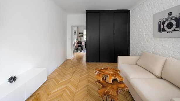 A modern living room with a herringbone wood floor, a white sofa, and a wooden coffee table. - Nowolipki Bright Studio (Warszawa)