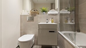 Un baño moderno con inodoro, lavabo y zona de ducha.