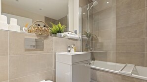 Un baño moderno con ducha envuelta en vidrio, un lavabo blanco y un inodoro.