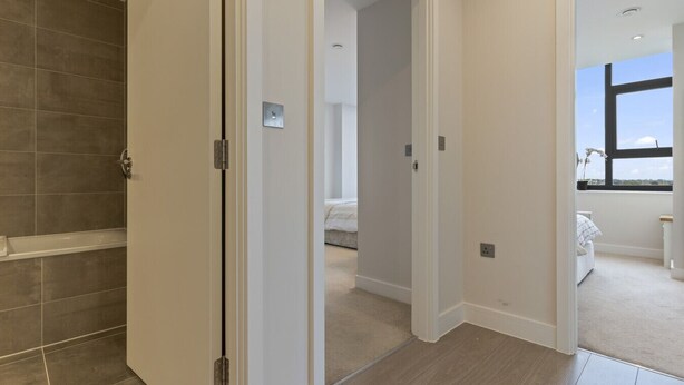 Un baño moderno con ducha, un dormitorio con cama y vistas al exterior a través de una ventana.