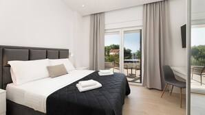 A modern hotel room with a large bed, a desk, and a balcony with a view. - Villa Hidden with heated pool (Kvarner - Hlapa) (Hlapa)