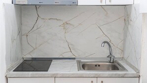 A kitchen with a marble backsplash, a stainless steel sink, and a built-in induction cooktop. - Green Luxe Suite 2 Private Hot Tub (Shkodër)