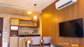 A modern kitchen with wooden cabinetry, a built-in stove, and a dining area with a table and chairs. - Complete apartment at AquaLand Resort in Salinópolis – sleeps 4 (Salinópolis)