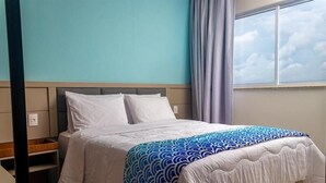 A hotel room with a bed, a nightstand, a window with curtains, and a view of the sky. - Complete apartment at AquaLand Resort in Salinópolis – sleeps 4 (Salinópolis)