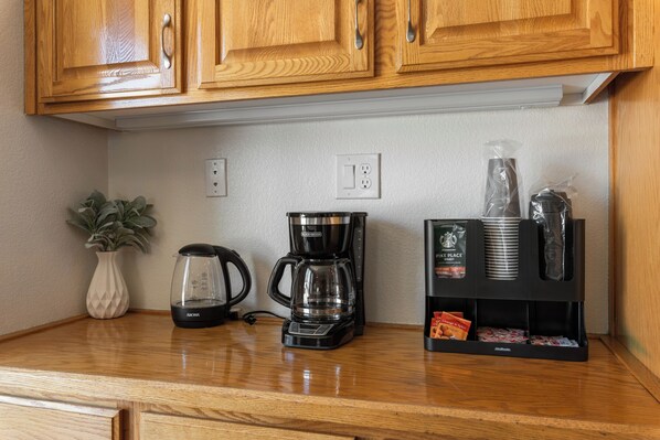 A kitchen with wooden cabinets, a coffee maker, a glass carafe, and a coffee pod holder.