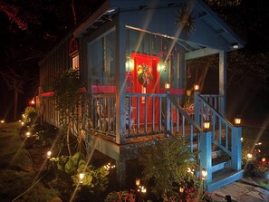 A small, two-story wooden structure with a red door and a porch. - The Gypsy Queen (Tishomingo)